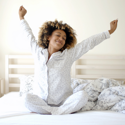 Woman stretching happily in bed after a good night's sleep